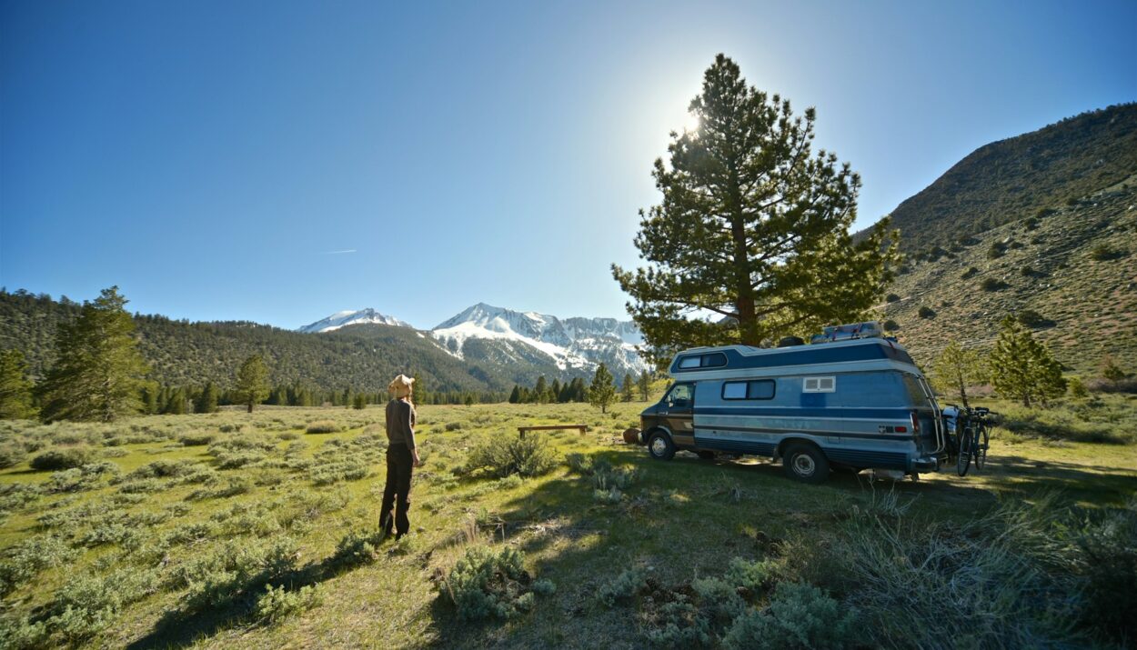 a woman standing in front of her camper van in nature