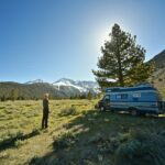 a woman standing in front of her camper van in nature