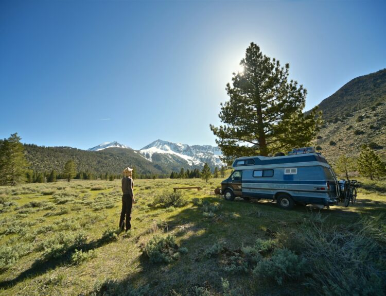 a woman standing in front of her camper van in nature