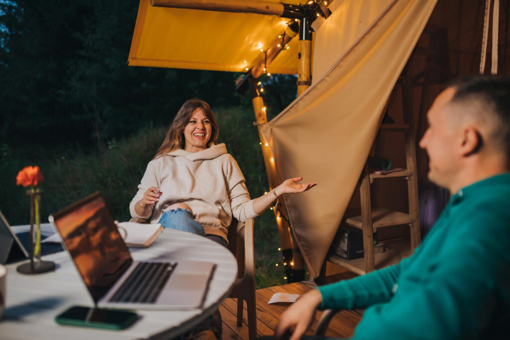 two poeple outside of their spot using a laptop to check the data of their RV park guests using campground software