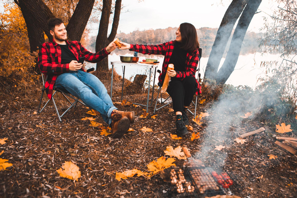 two people eating bread while cooking wnjoying a fall camping trip 