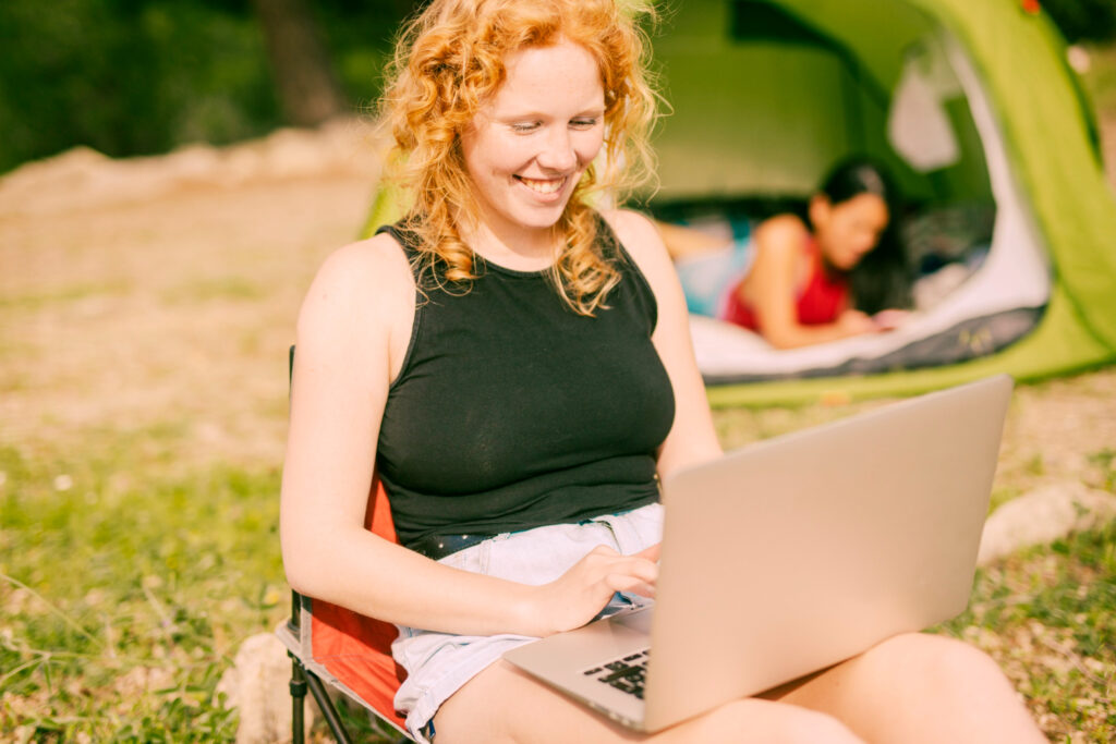 a woman making a booking using reservation software outside of her camping site 