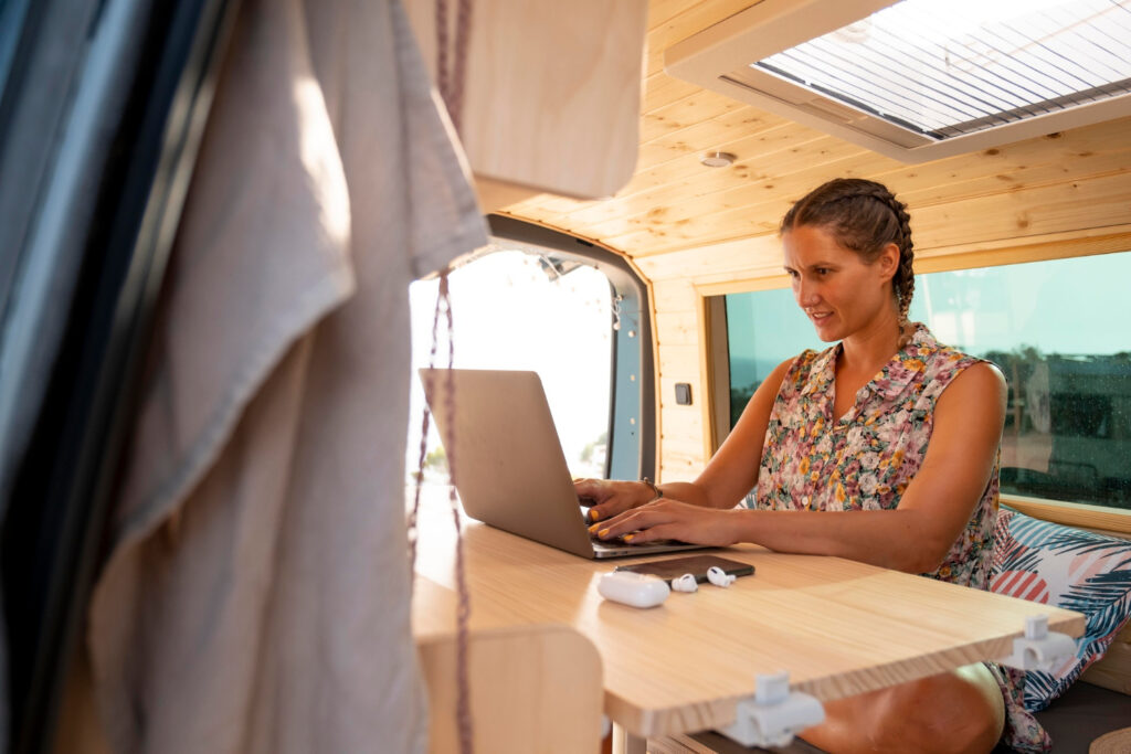 a woman using her laptop inside of her camper van using software for RV parks