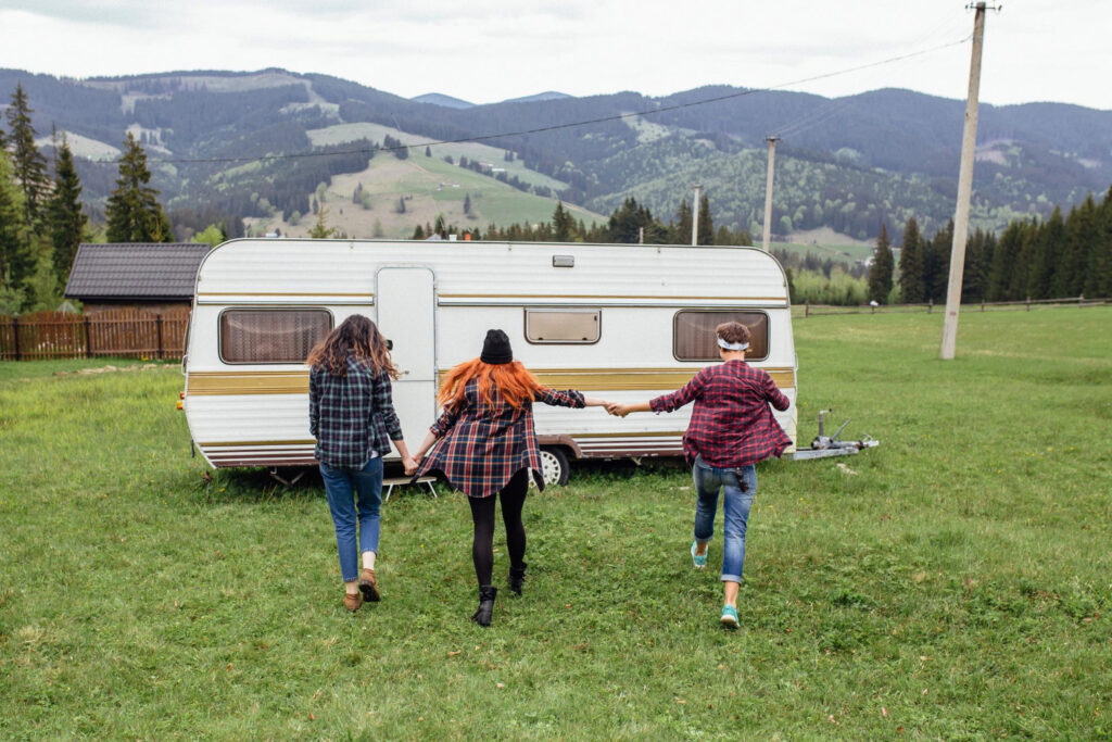 three friends going back to their camper van in a RV park while holding hands 