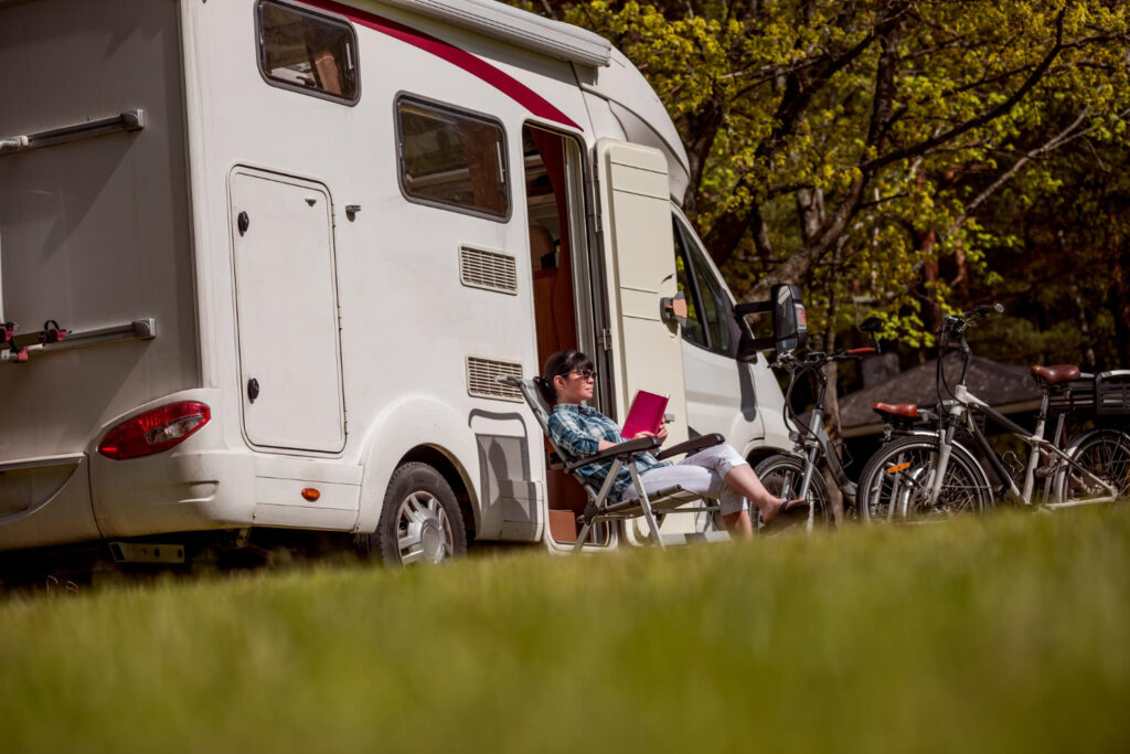 woman reading a bookg outside of her camper van 