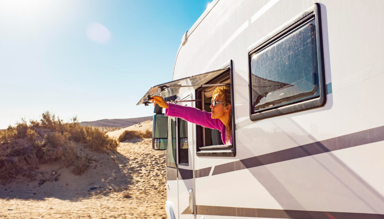 woman holding her window of a camper van in a RV park spot