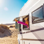 woman holding her window of a camper van in a RV park spot