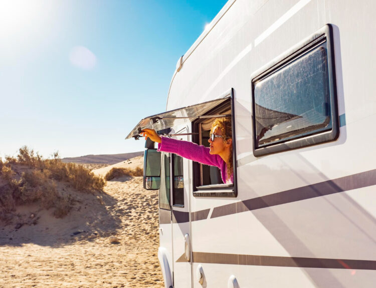 woman holding her window of a camper van in a RV park spot