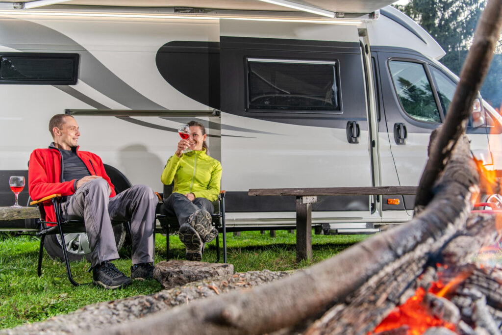 Two poeple holding a drink outside of their camper van enjoying a stay in an RV park 