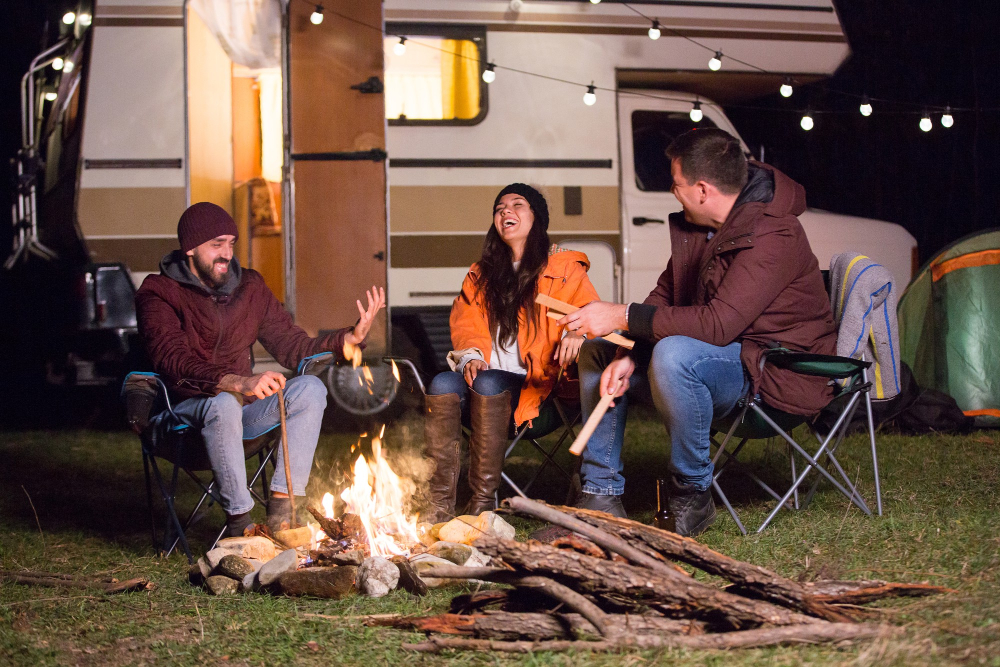 a group of friends enjoying a night out in their RV in front of a campfire having a fun camping experience 