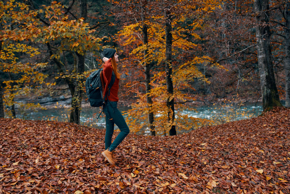 A woman hiking while camping in the fall in a forest full of leaves 