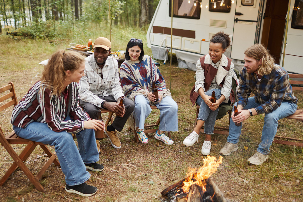 Group travelers enjoying their stay in a campsite in front of a campfire 